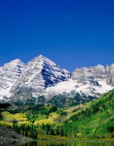 Снежные горы на фоне зеленого поля